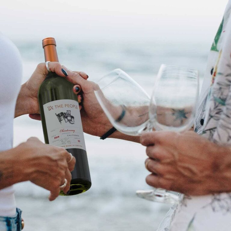 couple-enjoying-a-glass-of-wine-by-the-beach-TGYZ5JK-2